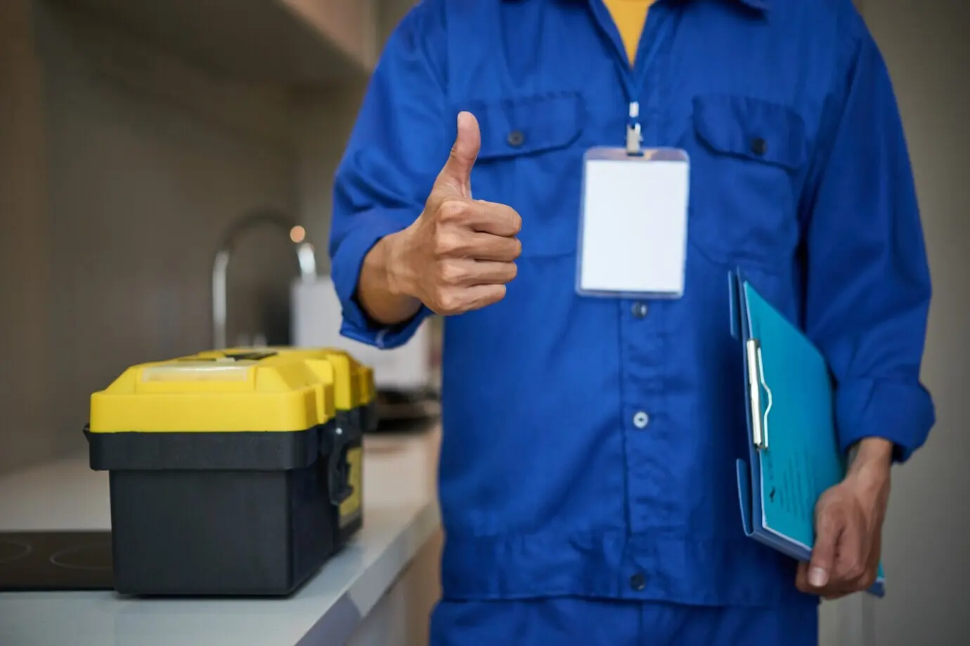 Unrecognizable male plumber standing near a kitchen sink and giving a thumbs-up.